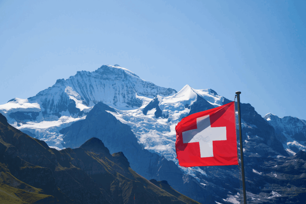 Bergpanorama der Schweizer Alpen mit Flagge, symbolisiert das neue Leben in der Schweiz.